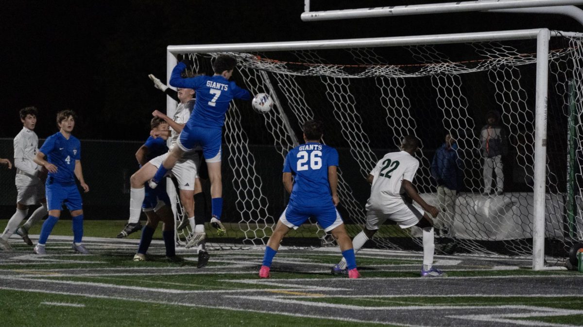 A Giant leaps toward the ball during a chaotic goal battle as teammates crowd the box to score the goal.