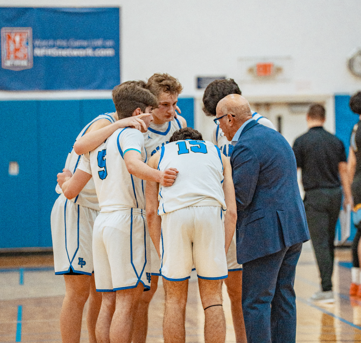 The starting lineup huddles with Coach Deutsch before tipping off the second half