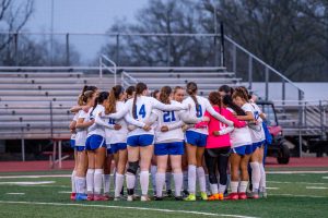 The HPHS varsity girls' soccer team in a huddle before their match against Deerfield  