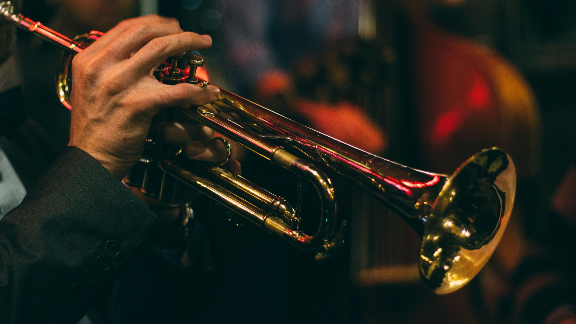A man plays a trumpet at a late night Jazz Club. Free to use under the Unsplash License
